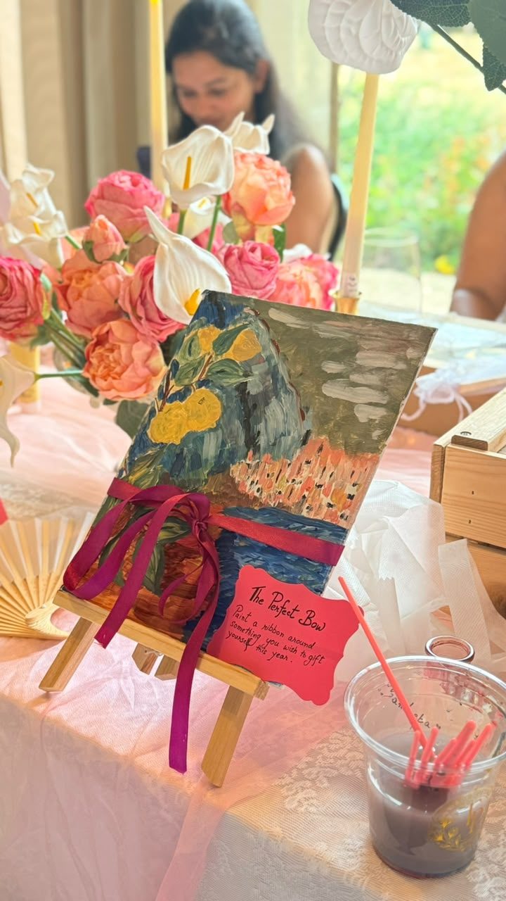 Paint and Prosecco activity — guest painting a ribbon-tied canvas, from a past Three Petals event